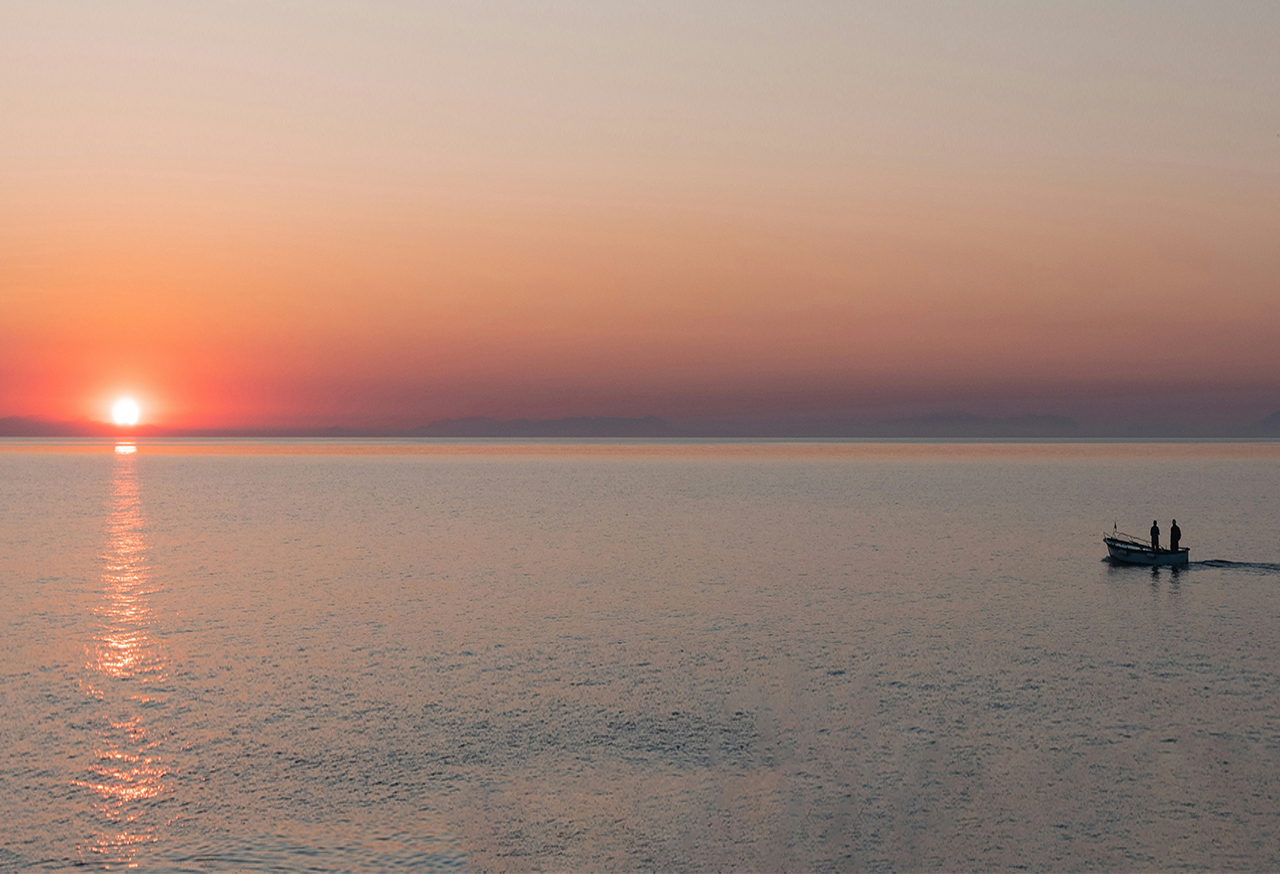 Small boat on water as the sun sets